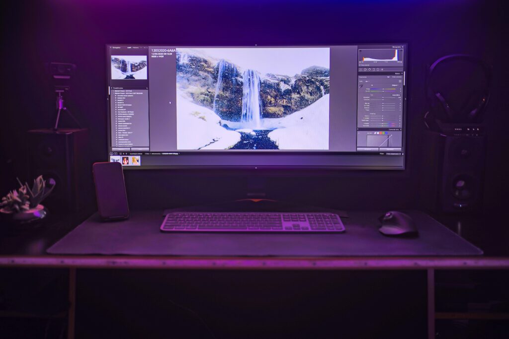 A wide monitor displays photo editing software with a waterfall image, ideal for a freelance graphic designer, graphic design studio, custom logo design, branding and identity design, professional graphic design services, graphic design for small business, digital design studio, affordable graphic design, creative design agency, or even a social media graphics designer. Wow so many words.